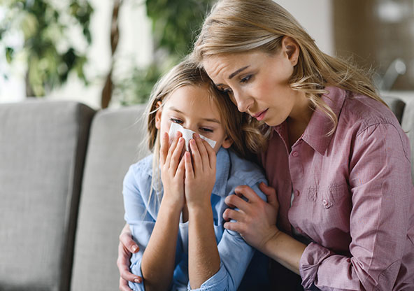 Mother tends to her daughter who is starting to have cold symptoms. 