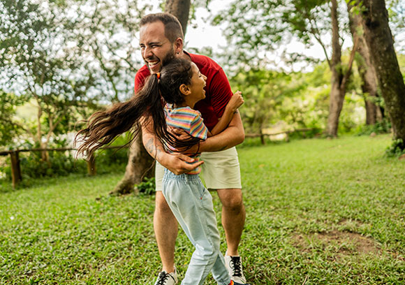 A dad and his young daughter play outside together