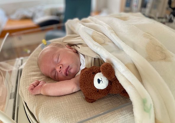 Baby Thierry Kobe is sleeping next to a teddy bear at CHRISTUS Children's