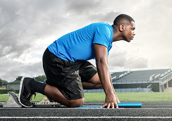 A man  on the starting blocks on a track, getting ready to run